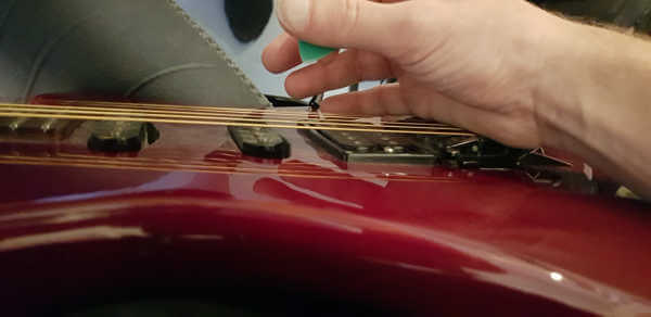 Anschlagen mit Plektrum Hand auf Bridge auflegen